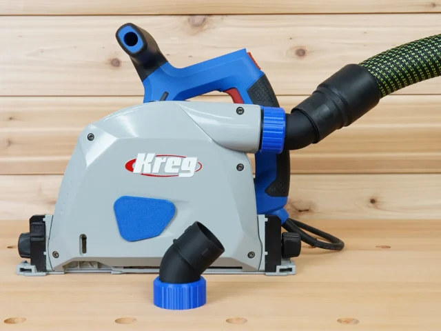 No snag dust port adapter mounted on a Kreg track saw, with hose angled upward and detachable blue coupling visible below