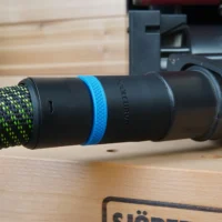 Black 36mm hose adapter with blue ring joining a green vacuum hose to a Porter Cable benchtop sander dust port