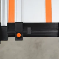 Black 3D-printed hose deflector mounted on Wen track saw guide rail with orange quick-release knob, viewed from below