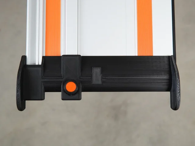 Black 3D-printed hose deflector mounted on Wen track saw guide rail with orange quick-release knob, viewed from below