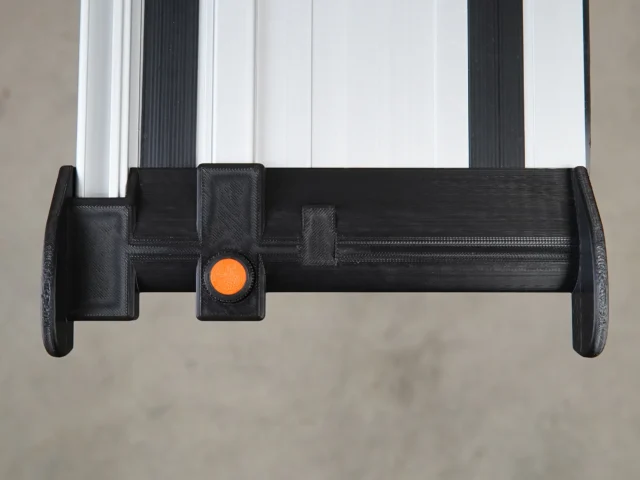 Black hose deflector mounted on guide rail with orange quick-release knob, front view