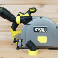 Black and yellow no snag dust port adapter mounted on a Ryobi ONE+ track saw, with green braided hose attached to the angled port