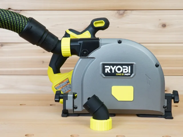 Black and yellow no snag dust port adapter mounted on a Ryobi ONE+ track saw, with green braided hose attached to the angled port