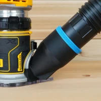Black 2-1/2 inch hose adapter cover installed on a DeWalt trim router base with vacuum hose attached