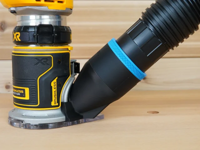 Black 2-1/2 inch hose adapter cover installed on a DeWalt trim router base with vacuum hose attached