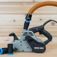 Black 1-1/4 inch hose adapter with blue band installed on a Porter Cable belt sander port, second adapter beside it