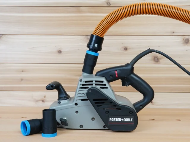 Black 1-1/4 inch hose adapter with blue band installed on a Porter Cable belt sander port, second adapter beside it