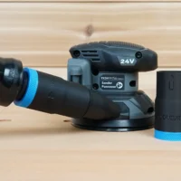 Black 1-1/4 inch hose adapter with blue collar beside a Flex sander, second adapter joining orange hose