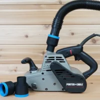 Black 1-7/8 inch hose adapter with blue band joining a vacuum hose to a Porter Cable belt sander, spare adapter beside it