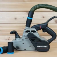 Black hose adapter with blue band linking a dust extractor hose to a Porter Cable belt sander, spare adapter alongside