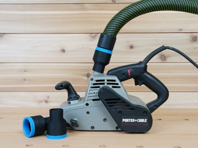 Black 36mm hose adapter with blue band installed on a Porter Cable belt sander dust port, second adapter beside it