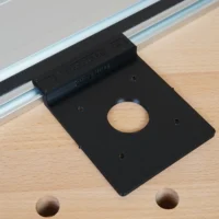 Black FLEX 24v router guide rail adapter mounted on aluminum track rail, showing circular opening and mounting holes
