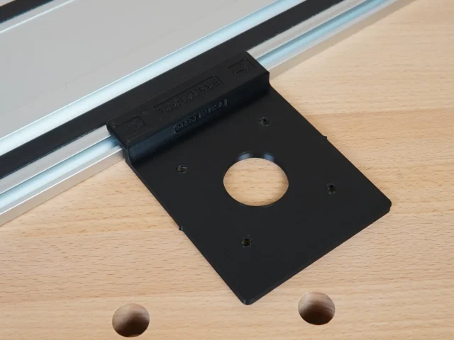 Black FLEX 24v router guide rail adapter mounted on aluminum track rail, showing circular opening and mounting holes