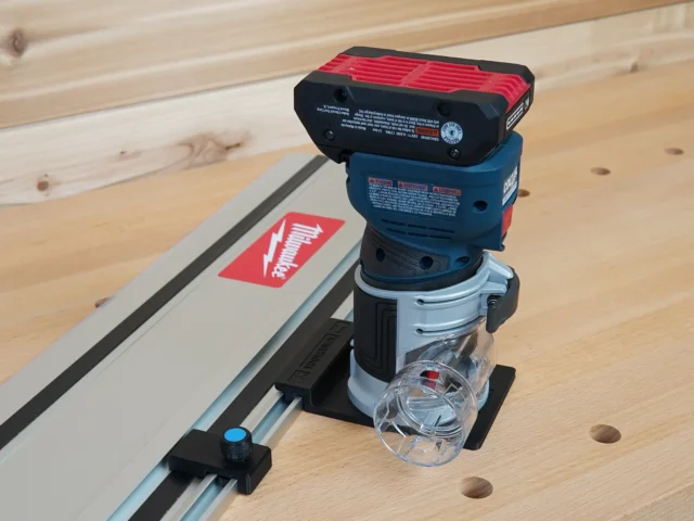 Bosch Colt 18v router mounted on a guide rail adapter, positioned on a track saw rail with holes visible on the workpiece
