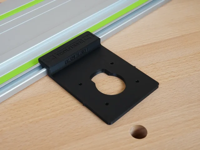 Black plastic guide rail adapter mounted on a Festool track saw rail, with a circular opening visible on the flat base