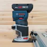 ToolCurve guide rail adapter mounted on a Bosch GFK18v Colt router, connected to a guide rail track on wooden surface