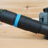 Black hose adapter with blue identification band attached to a Flex sander's dust port, connected to a green-and-black braided hose