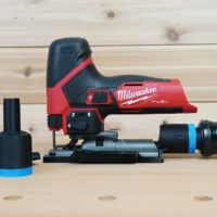 Black 1-1/4 inch hose adapter with blue collar installed on a Milwaukee M12 Fuel jig saw, second adapter alongside