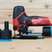 Black ToolCurve 1-7/8 inch hose adapter with blue ring beside a Milwaukee M12 Fuel jig saw and vac hose