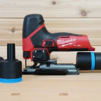 Black 36mm ToolCurve hose adapter parts beside a Milwaukee M12 Fuel jig saw, with hose cuff connected at right