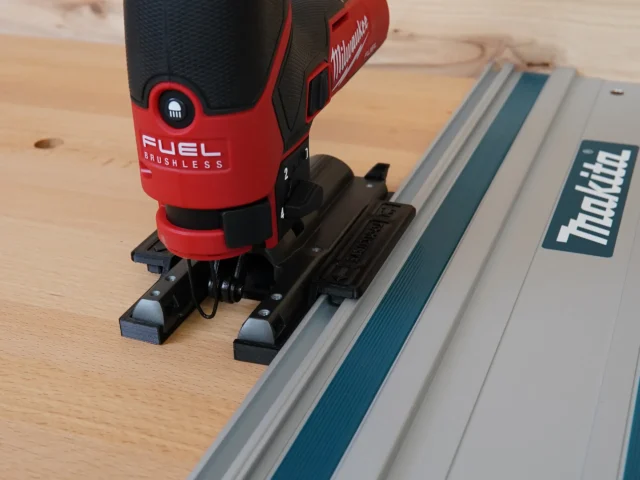 Milwaukee M12 Fuel jig saw mounted on a track saw guide rail via black plastic adapter with dual contact feet