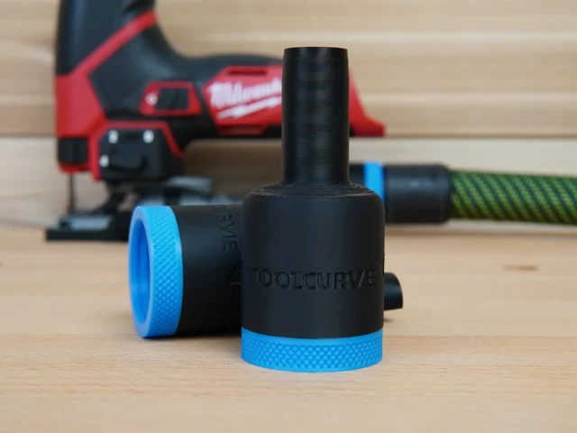 Black hose adapter with blue grip rings attached to Milwaukee M12 Fuel jig saw dust port, shown on workbench with jig saw in background