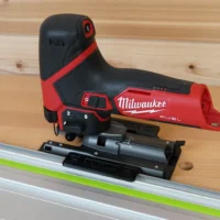 Milwaukee M12 Fuel jig saw mounted on an aluminum guide rail with a black plastic adapter base