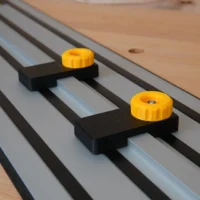 Two black plastic limit stops with yellow knobs mounted on parallel Dewalt guide rails