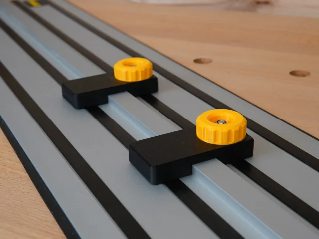 Two black plastic limit stops with yellow knobs mounted on parallel Dewalt guide rails