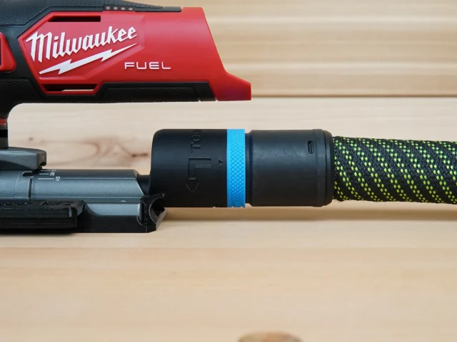 Black hose adapter with blue band attached to Milwaukee M12 Fuel Jig Saw dust port, connected to green and yellow braided hose