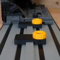 Two black limit stops with yellow knobs mounted on a Dewalt track saw guide rail, positioned at different points along the track
