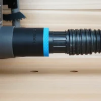 Black ToolCurve 1-7/8 in hose adapter with blue ring joining a ribbed vacuum hose to a Ryobi table saw dust port
