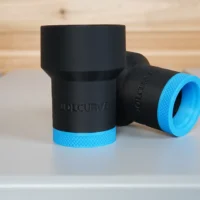 Two black ToolCurve hose adapters with blue grip bands, cylindrical bodies shown at different angles on a workbench