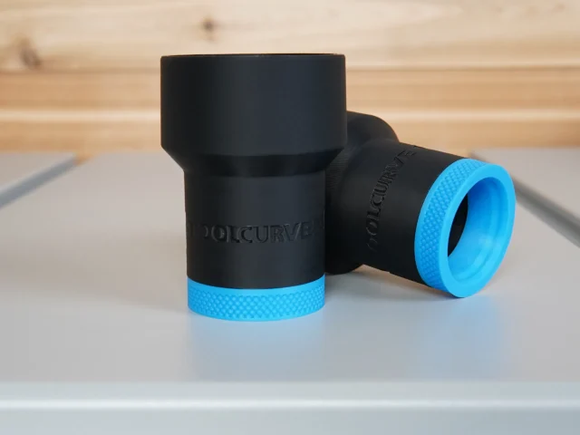 Two black ToolCurve hose adapters with blue grip bands, cylindrical bodies shown at different angles on a workbench