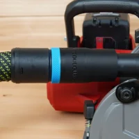 Black hose adapter with blue band attached to Milwaukee M18 circular saw dust port, connected to green and yellow braided hose
