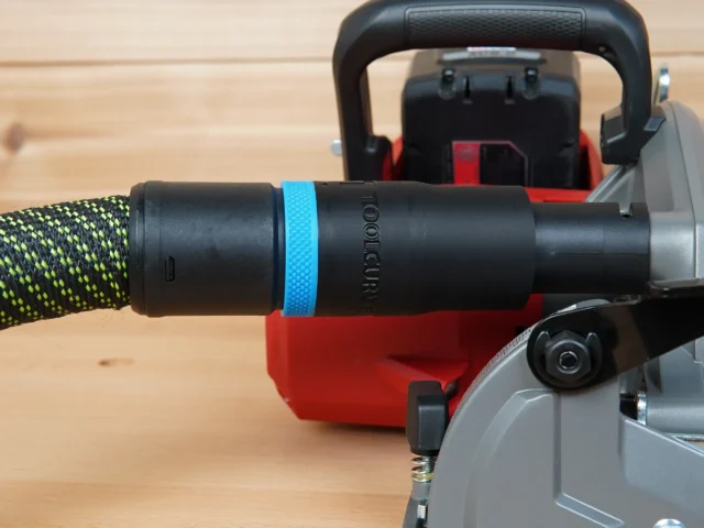 Black hose adapter with blue band attached to Milwaukee M18 circular saw dust port, connected to green and yellow braided hose