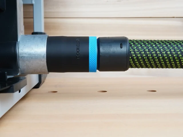 Black ToolCurve 36mm hose adapter with blue ring linking a green-striped hose to a FLEX table saw dust port