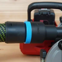 Black ToolCurve 36mm hose adapter with blue grip ring joining a green hose to a Milwaukee M18 rear handle circular saw dust port