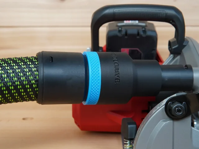 Black ToolCurve 36mm hose adapter with blue grip ring joining a green hose to a Milwaukee M18 rear handle circular saw dust port