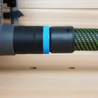 Black ToolCurve 36mm hose adapter with blue ring joining a green vacuum hose to a Ryobi table saw dust port