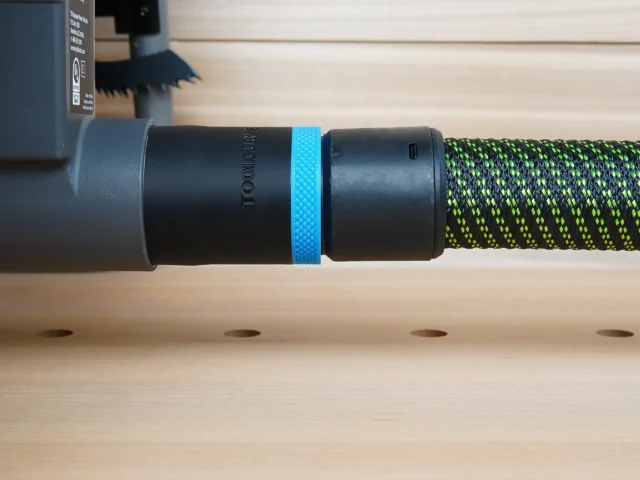 Black ToolCurve 36mm hose adapter with blue ring joining a green vacuum hose to a Ryobi table saw dust port