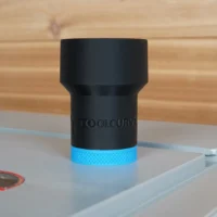 Black ToolCurve hose adapter with blue band, standing on aluminum track, wooden workbench in background