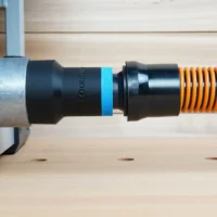 Black ToolCurve 1-1/4 inch hose adapter with blue ring joining an orange vacuum hose to a FLEX table saw dust port
