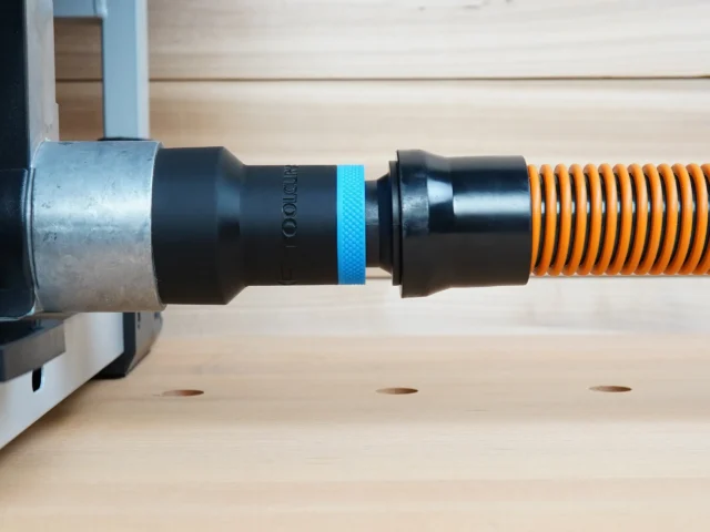 Black ToolCurve 1-1/4 inch hose adapter with blue ring joining an orange vacuum hose to a FLEX table saw dust port