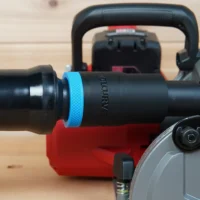 Black ToolCurve 1-1/4in hose adapter with blue grip ring joining an orange hose to a Milwaukee M18 rear handle circular saw dust port