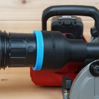 Black 2-1/2 inch hose adapter with blue grip ring joining a vacuum hose to a Milwaukee M18 rear handle circular saw dust port
