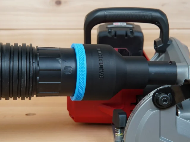 Black 2-1/2 inch hose adapter with blue grip ring joining a vacuum hose to a Milwaukee M18 rear handle circular saw dust port