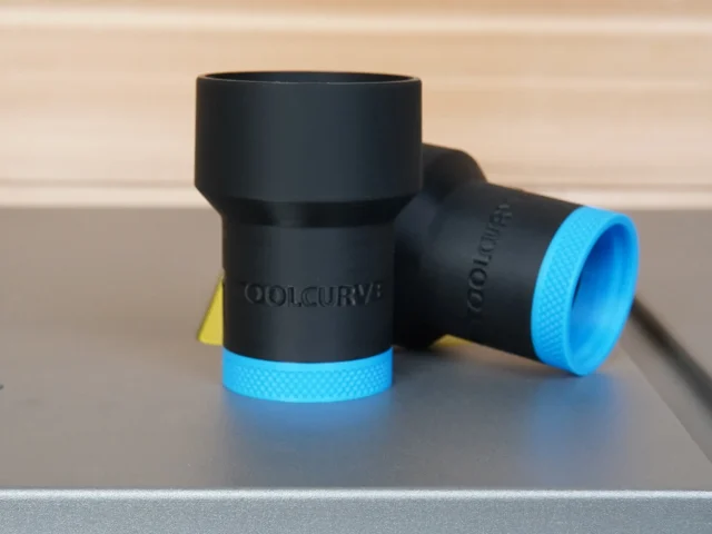 Black cylindrical ToolCurve hose adapter with blue grip bands, shown standalone next to a ruler for scale