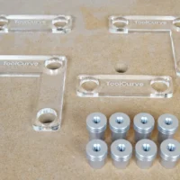 Two clear acrylic 90-degree corner fences, two straight stops, and eight aluminum 20mm bench dogs on an MDF top