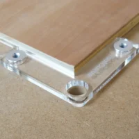 Clear acrylic fence stops with aluminum bench dogs installed in 20mm workbench holes, showing corner and straight stop configurations